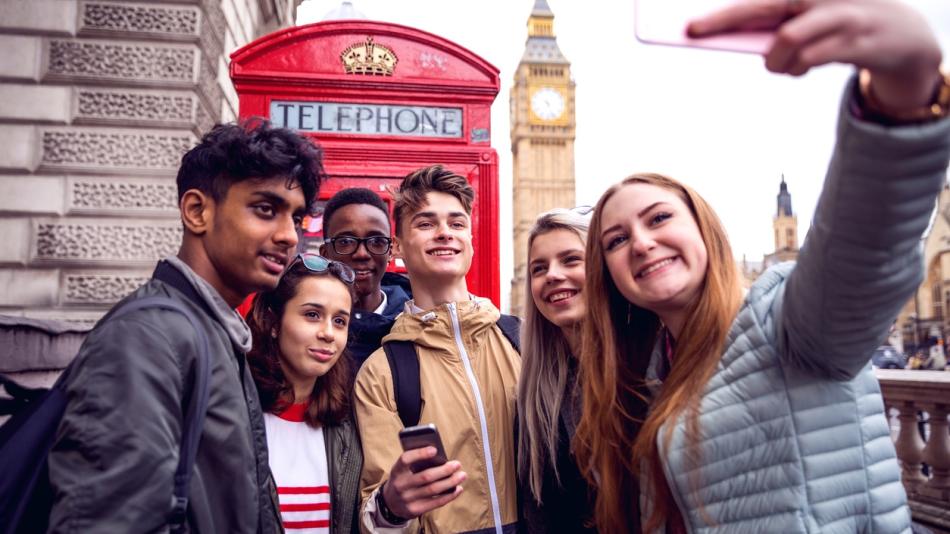 Group of young people taking a selfie, with a UK red phone box and Big Ben in the background.