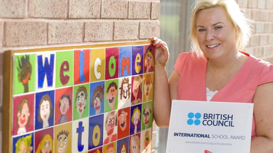 Teacher proudly holding their International School Award certificate.