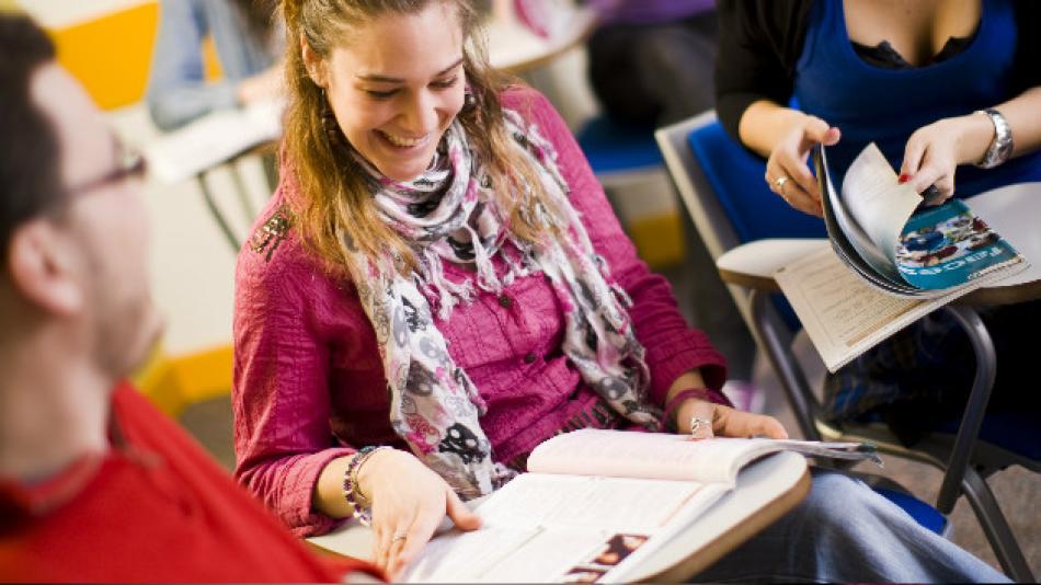 Adults sat at desks looking at course books