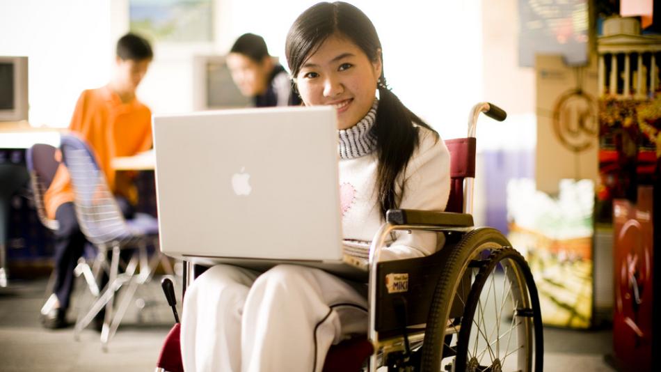 Wheelchair user smiling at her laptop