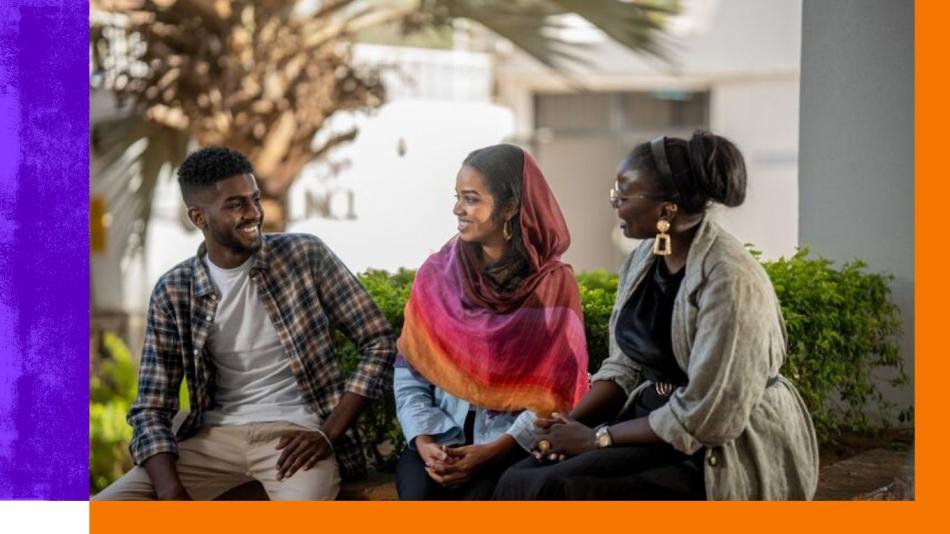Two women and a man sat outside having a conversation.