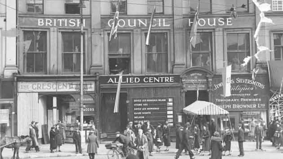 The British Council House many years ago. A very grand building with flags draped outside and a busy street scene out front 