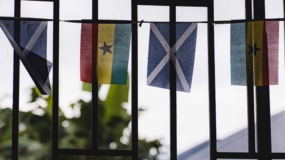 Four flags fly outside a window demonstrating the partnership between Scotland and Ghana