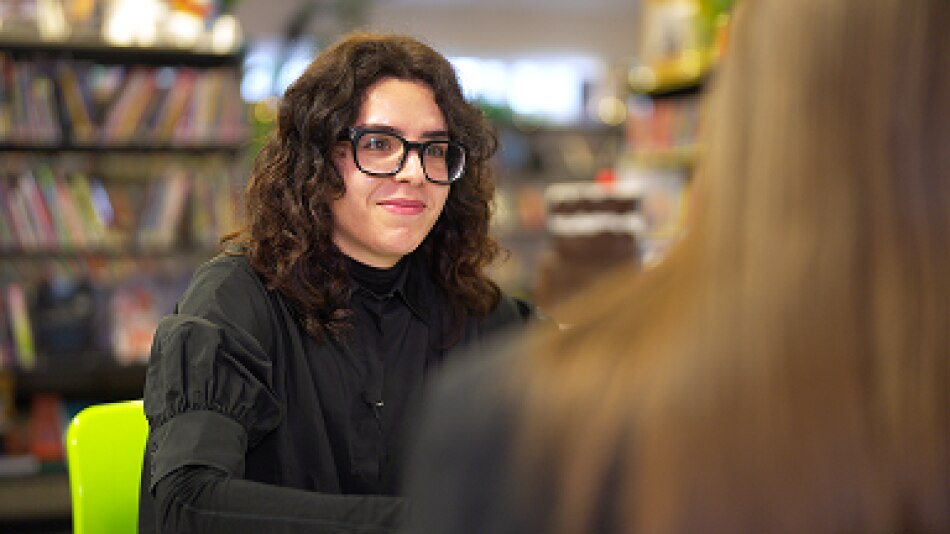 Language assistant sits in school library with pupil