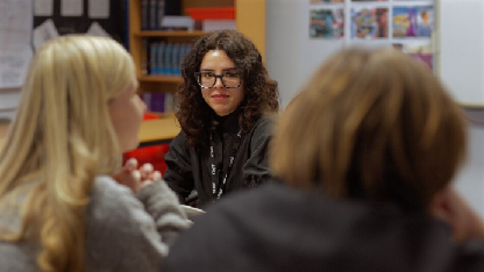 Spanish language assistant speaking with two pupils in class
