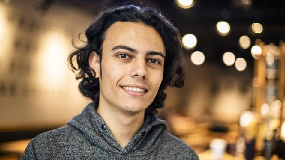 Young person in grey hoodie smiling at the camera