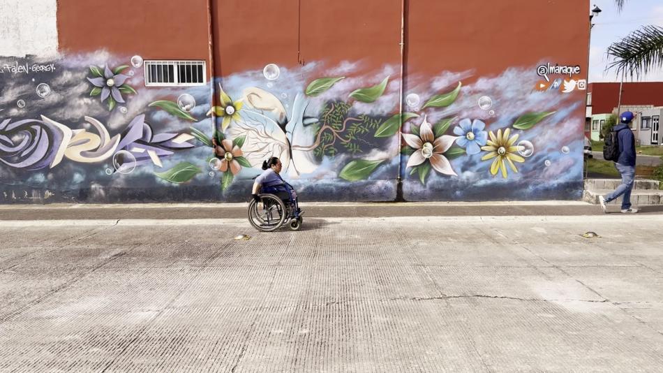 A woman using a wheelchair passing a street mural.