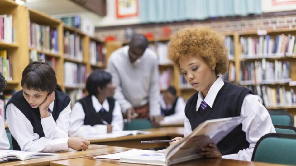 Young female students reads a book in the school library
