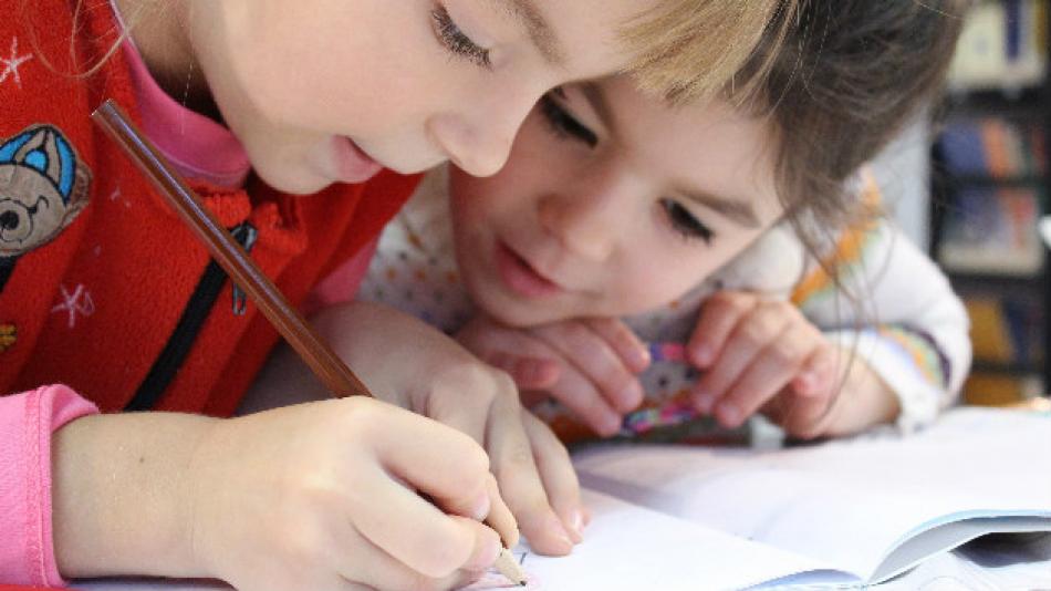 Two young girls writing in an exercise book