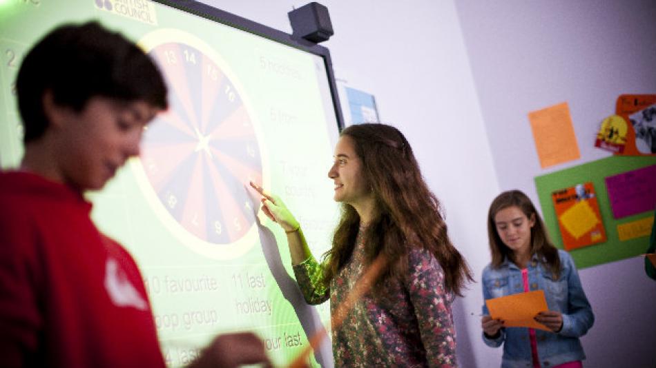 Teenage children using an interactive board in class.