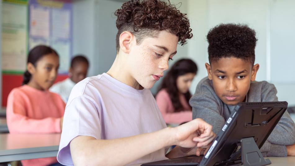Two boys working together in class on a tablet.