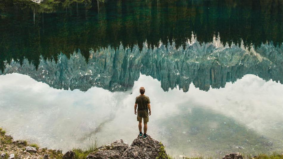 man standing on rock in front of lake