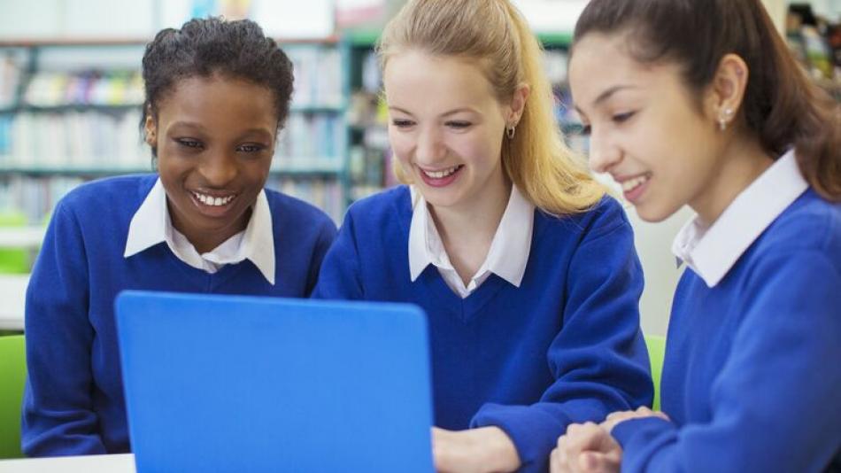 Three young women working with a laptop.