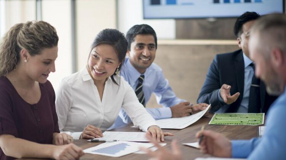 Men and women sat at a table having a meeting