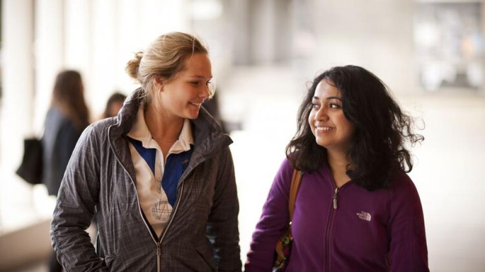 Two women students chat together in the corridor
