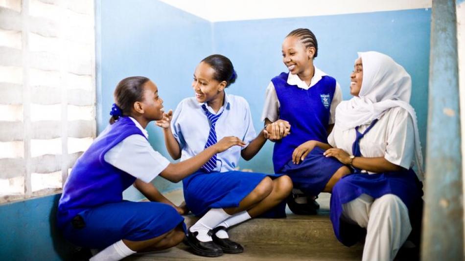 Four young Kenya students sit together chatting